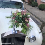 Trouwauto bloemen in veldboeket stijl met diverse soorten groen en roze zomer bloemen Trouwauto